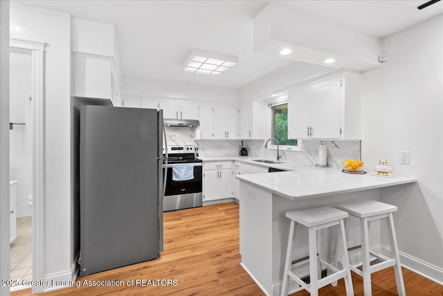 5195 E Brookfield Dr, East Lansing, MI 48823 - kitchen featuring stainless steel range with electric cooktop, freestanding refrigerator, under cabinet range hood, a peninsula, and a sink