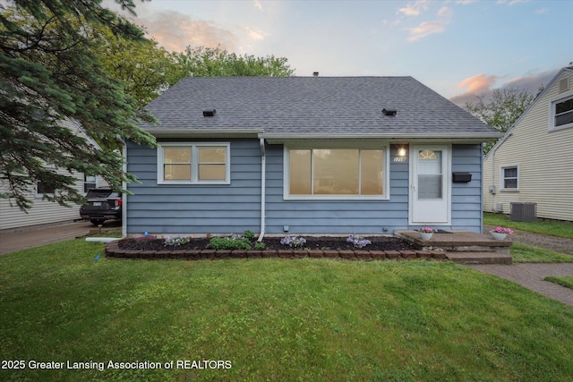 1718 Victor Ave, Lansing, MI 48910 - bungalow-style home featuring roof with shingles, central air condition unit, and a yard
