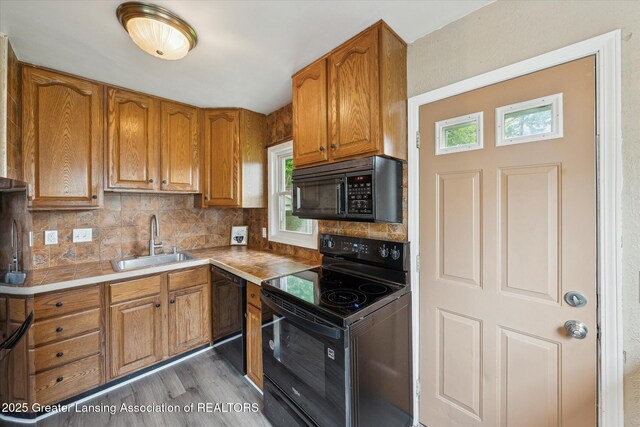 1718 Victor Ave, Lansing, MI 48910 - kitchen featuring black appliances, a sink, brown cabinets, decorative backsplash, and light wood finished floors