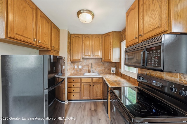 1718 Victor Ave, Lansing, MI 48910 - kitchen featuring black appliances, a sink, light wood finished floors, backsplash, and brown cabinets