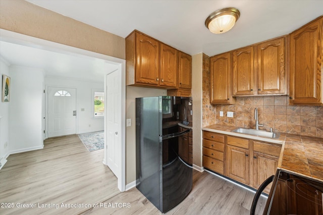1718 Victor Ave, Lansing, MI 48910 - kitchen featuring black appliances, light wood-type flooring, a sink, decorative backsplash, and brown cabinetry