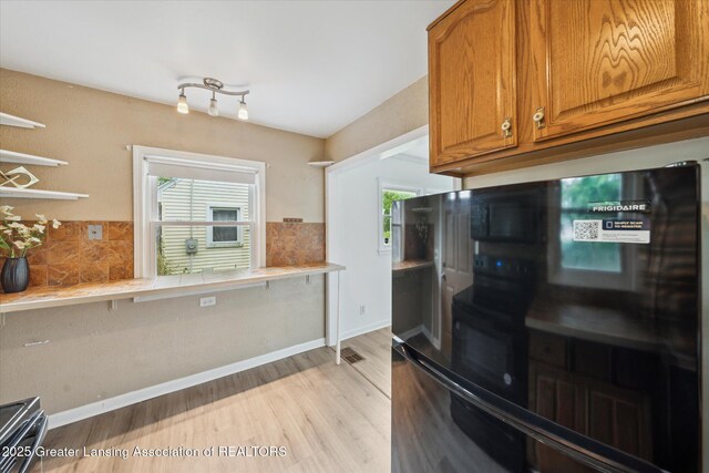 1718 Victor Ave, Lansing, MI 48910 - kitchen with freestanding refrigerator, brown cabinets, backsplash, and light wood-style flooring