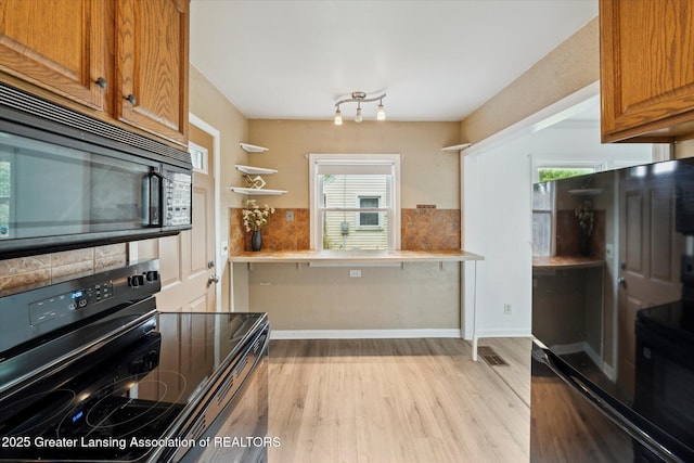 1718 Victor Ave, Lansing, MI 48910 - kitchen featuring black appliances, light wood-type flooring, brown cabinetry, and light countertops