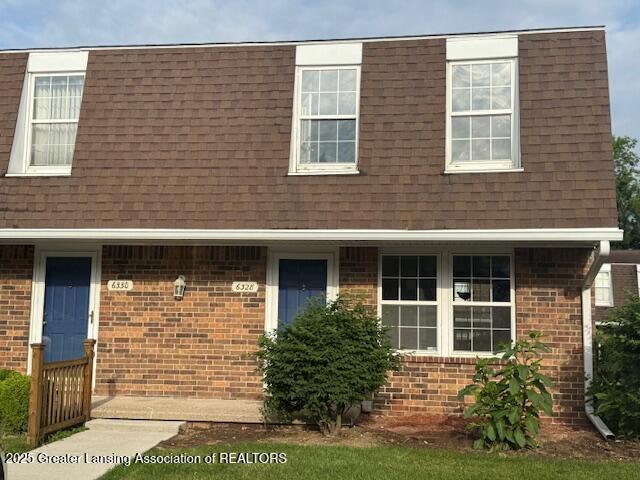 6328 Beechfield Dr, Lansing, MI 48911 - view of front of house featuring a shingled roof, brick siding, and mansard roof