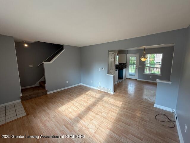 6328 Beechfield Dr, Lansing, MI 48911 - unfurnished living room featuring light wood-type flooring and stairway