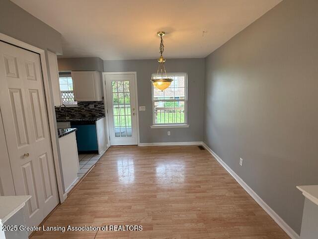 6328 Beechfield Dr, Lansing, MI 48911 - unfurnished dining area featuring light wood-style flooring and baseboards