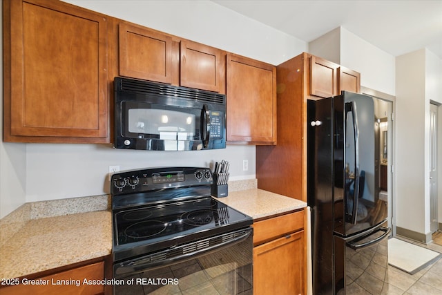 500 E Michigan Ave Unit 417, Lansing, MI 48912 - kitchen featuring black appliances, light tile patterned floors, brown cabinetry, and light stone counters