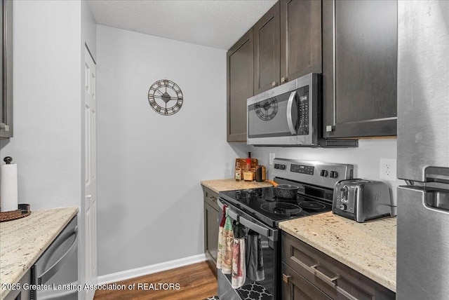 12947 Townsend Dr Unit 412, Grand Ledge, MI 48837 - kitchen with stainless steel appliances, dark brown cabinetry, dark wood finished floors, baseboards, and a textured ceiling