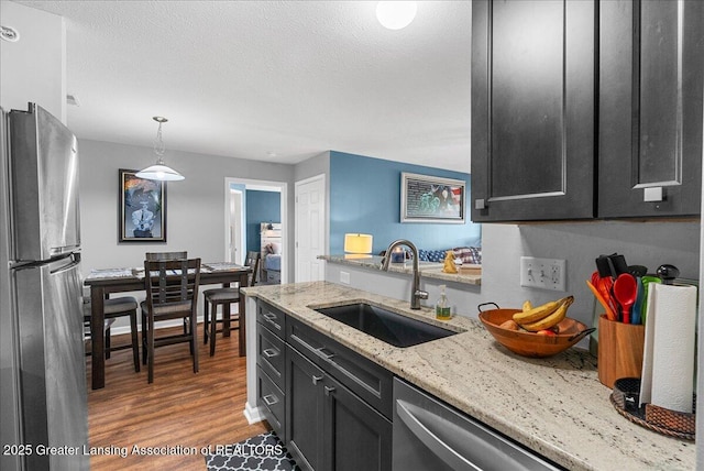 12947 Townsend Dr Unit 412, Grand Ledge, MI 48837 - kitchen with stainless steel appliances, a sink, dark cabinetry, wood finished floors, and a textured ceiling