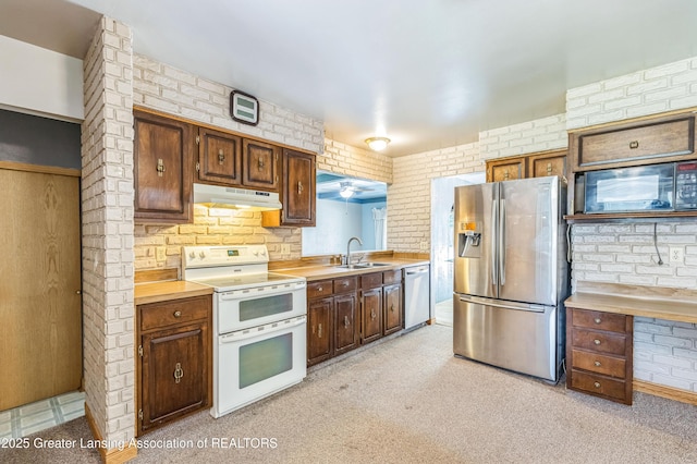 1802 Rockdale Ave, Lansing, MI 48917 - kitchen with stainless steel appliances, a sink, under cabinet range hood, light countertops, and brick wall