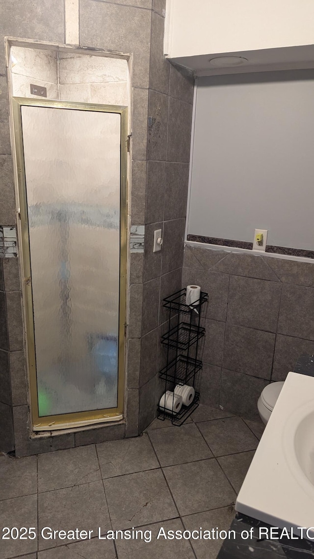 1515 Prospect St, Lansing, MI 48912 - bathroom featuring tile walls, tile patterned floors, a stall shower, toilet, and a sink