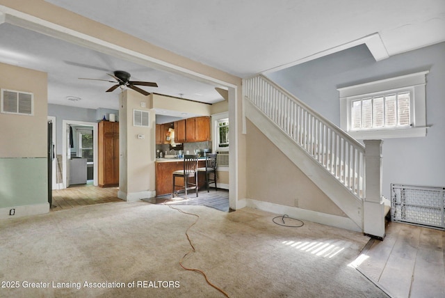 1515 Prospect St, Lansing, MI 48912 - living area featuring light colored carpet, a ceiling fan, stairway, and light wood-style floors