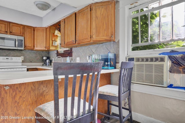 1515 Prospect St, Lansing, MI 48912 - kitchen with stainless steel microwave, electric stove, backsplash, brown cabinets, and light countertops