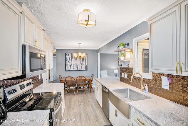 1808 Cadillac Ave, Lansing, MI 48917 - kitchen with appliances with stainless steel finishes, a chandelier, backsplash, a sink, and crown molding