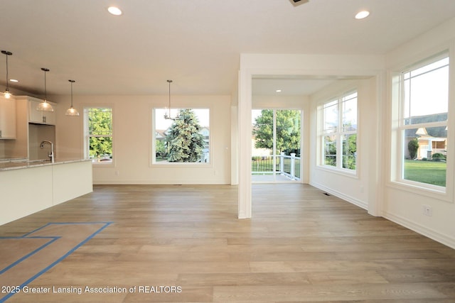 629 Aquila Dr, East Lansing, MI 48823 - unfurnished living room with light wood-style floors, baseboards, recessed lighting, and a sink