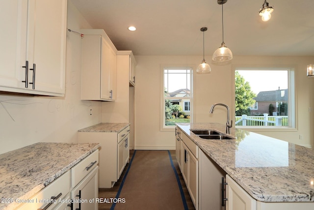 629 Aquila Dr, East Lansing, MI 48823 - kitchen with a sink, light stone counters, white cabinetry, recessed lighting, and a kitchen island with sink