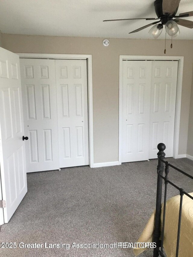 4615 Hughes Rd, Lansing, MI 48910 - unfurnished bedroom featuring carpet flooring, two closets, baseboards, and a ceiling fan