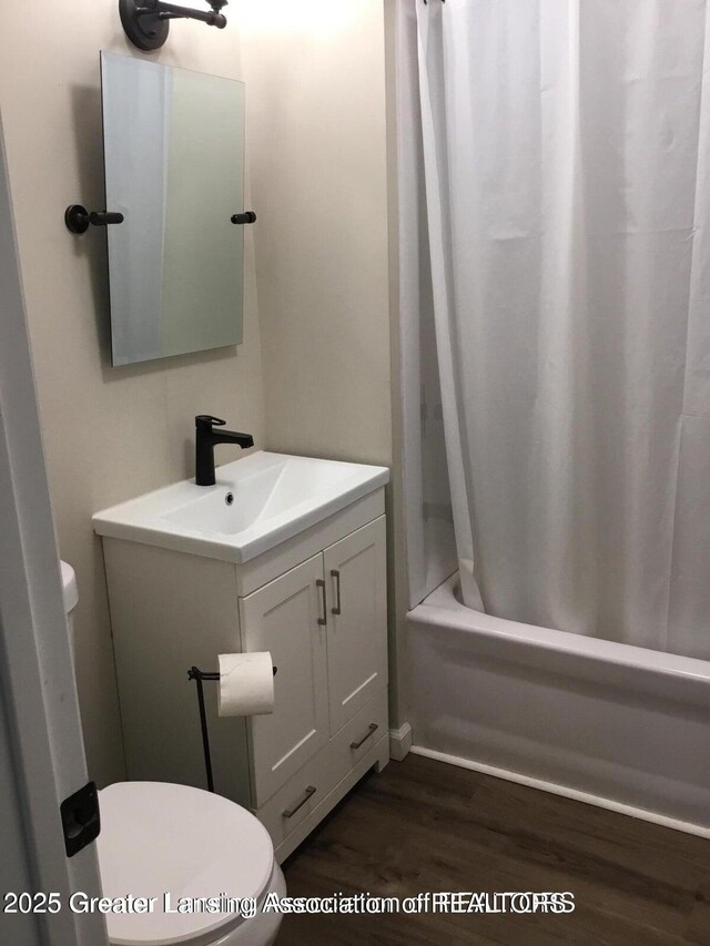 4615 Hughes Rd, Lansing, MI 48910 - bathroom featuring toilet, wood finished floors, vanity, and shower / tub combo with curtain