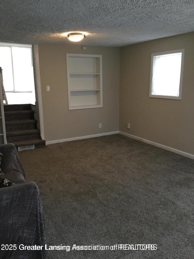 4615 Hughes Rd, Lansing, MI 48910 - unfurnished living room with a textured ceiling, stairway, carpet floors, built in shelves, and baseboards