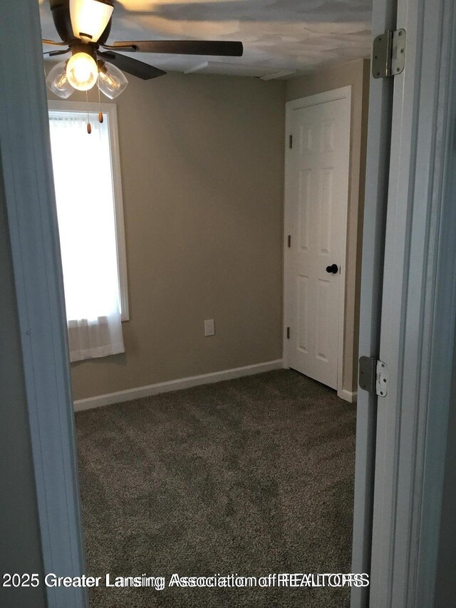4615 Hughes Rd, Lansing, MI 48910 - empty room featuring dark carpet, a ceiling fan, and baseboards