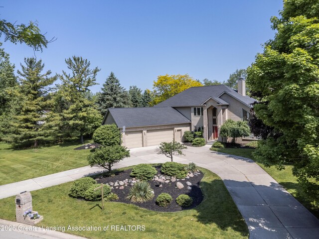 1120 Nautical Dr, Okemos, MI 48864 - view of front of house featuring a front lawn, a garage, a chimney, and driveway