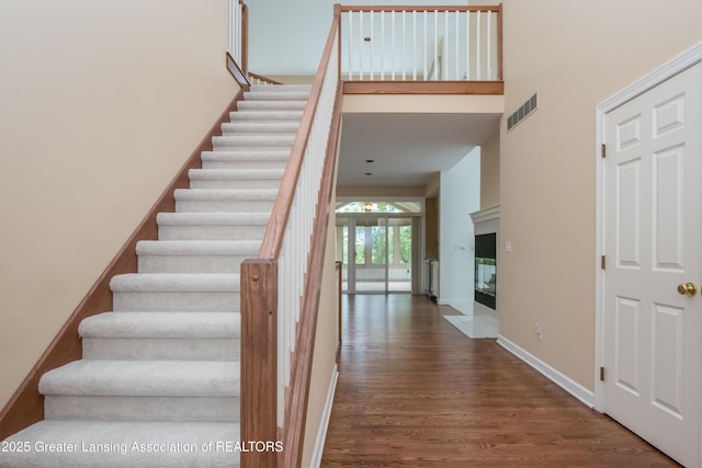 1120 Nautical Dr, Okemos, MI 48864 - staircase with wood finished floors, a multi sided fireplace, baseboards, and a high ceiling