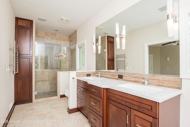 1120 Nautical Dr, Okemos, MI 48864 - bathroom featuring toilet, a stall shower, double vanity, tasteful backsplash, and a towel warmer