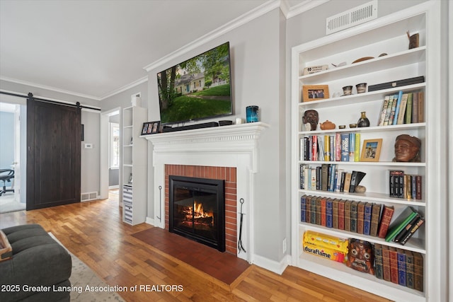 942 W Grand River Ave, East Lansing, MI 48823 - living room with crown molding, wood finished floors, a brick fireplace, and a barn door