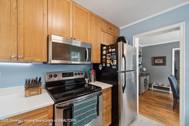 942 W Grand River Ave, East Lansing, MI 48823 - kitchen with appliances with stainless steel finishes, ornamental molding, light wood-style flooring, and light countertops