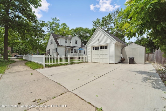 942 W Grand River Ave, East Lansing, MI 48823 - view of front of house featuring an outbuilding, a garage, concrete driveway, and a fenced front yard