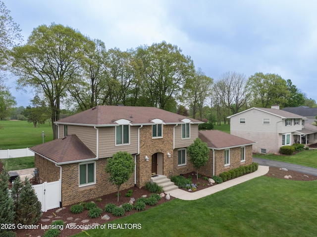 6108 Skyline Dr, East Lansing, MI 48823 - traditional home with brick siding, a gate, and a shingled roof