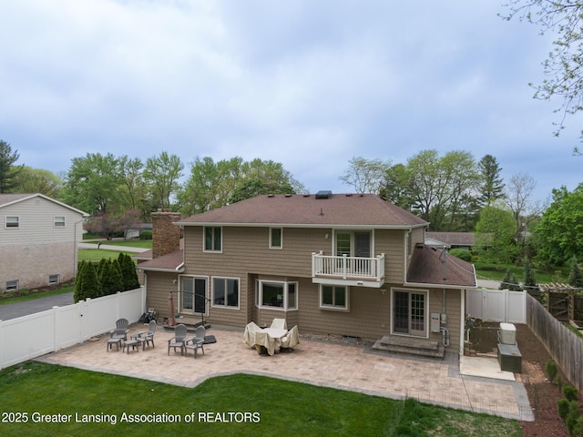 6108 Skyline Dr, East Lansing, MI 48823 - rear view of property featuring a balcony, a patio, a chimney, and a shingled roof