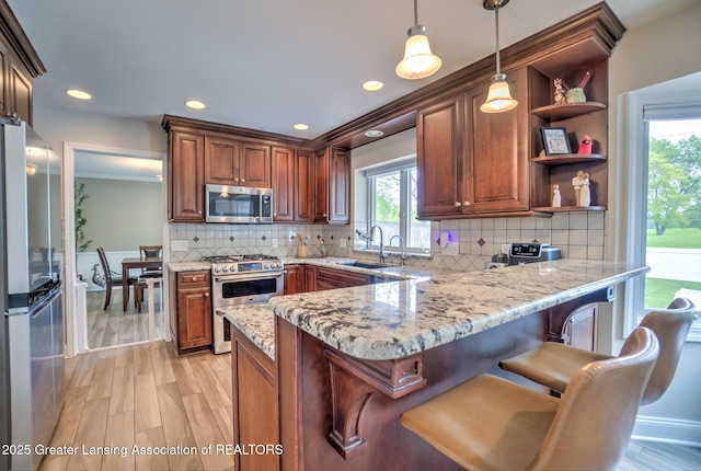 6108 Skyline Dr, East Lansing, MI 48823 - kitchen with stainless steel appliances, a peninsula, a sink, open shelves, and pendant lighting