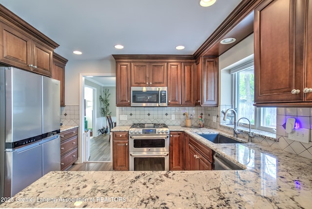 6108 Skyline Dr, East Lansing, MI 48823 - kitchen with stainless steel appliances, a sink, decorative backsplash, light stone countertops, and recessed lighting