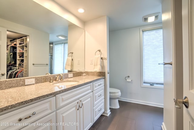 6108 Skyline Dr, East Lansing, MI 48823 - full bathroom with vanity, toilet, baseboards, and a walk in closet