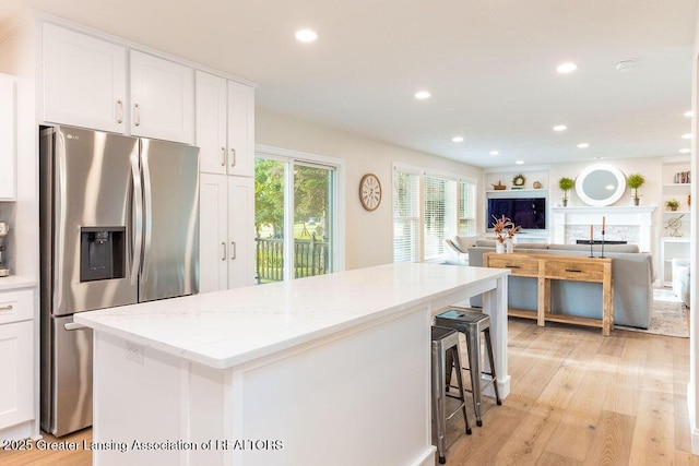 5871 Green Rd, Haslett, MI 48840 - kitchen with stainless steel fridge with ice dispenser, a center island, white cabinets, open floor plan, and light wood-type flooring