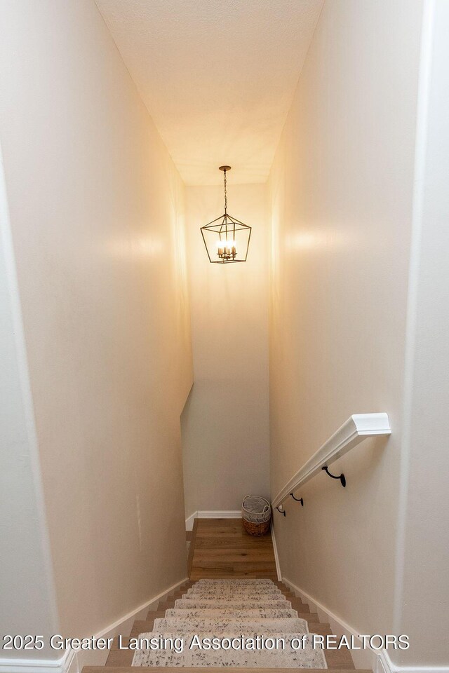 5871 Green Rd, Haslett, MI 48840 - staircase featuring a chandelier and wood finished floors
