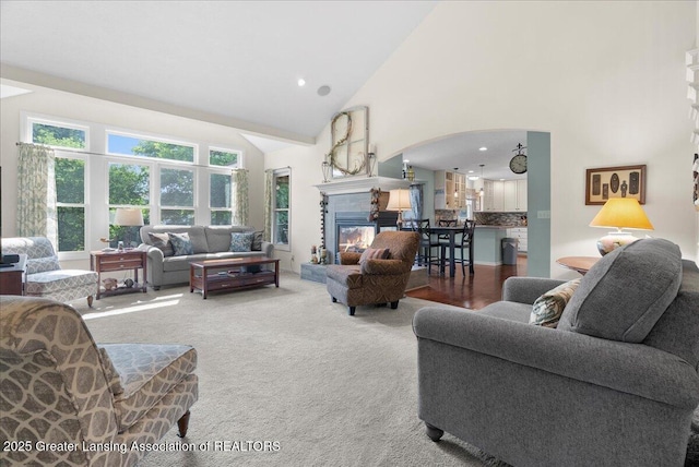 2134 Cedar Bend Dr, Holt, MI 48842 - carpeted living area featuring high vaulted ceiling, arched walkways, a glass covered fireplace, and recessed lighting