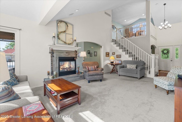 2134 Cedar Bend Dr, Holt, MI 48842 - living room featuring stairway, arched walkways, a tiled fireplace, carpet, and a chandelier