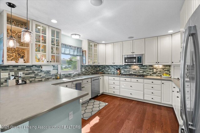 2134 Cedar Bend Dr, Holt, MI 48842 - kitchen featuring appliances with stainless steel finishes, dark wood-style floors, white cabinetry, decorative backsplash, and glass insert cabinets