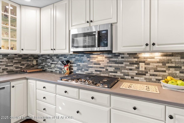 2134 Cedar Bend Dr, Holt, MI 48842 - kitchen featuring appliances with stainless steel finishes, white cabinets, tasteful backsplash, glass insert cabinets, and light countertops