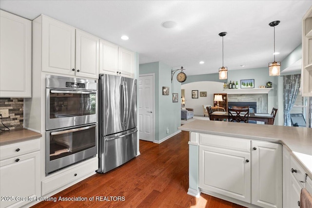 2134 Cedar Bend Dr, Holt, MI 48842 - kitchen with stainless steel appliances, tasteful backsplash, white cabinetry, dark wood-style floors, and arched walkways
