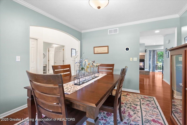 2134 Cedar Bend Dr, Holt, MI 48842 - dining area with wood finished floors, crown molding, and arched walkways