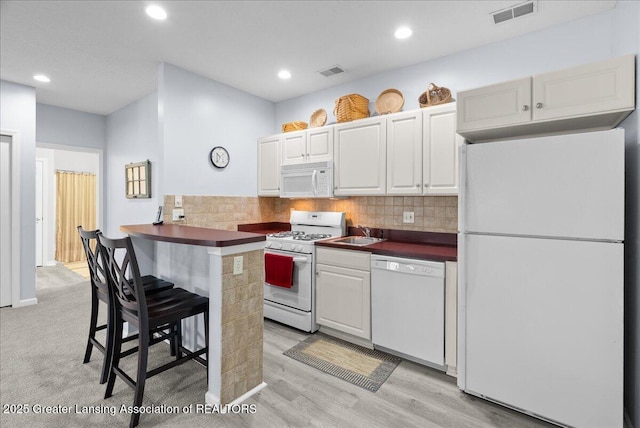 2134 Cedar Bend Dr, Holt, MI 48842 - kitchen with white appliances, dark countertops, a breakfast bar, decorative backsplash, and recessed lighting