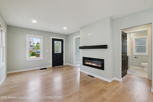 2506 W Kalamazoo St, Lansing, MI 48917 - foyer entrance featuring light wood finished floors, a glass covered fireplace, baseboards, and recessed lighting