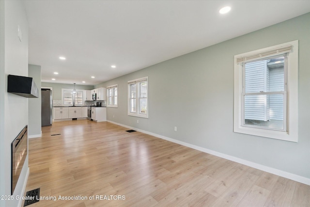 2506 W Kalamazoo St, Lansing, MI 48917 - unfurnished living room featuring light wood-style flooring, recessed lighting, baseboards, and a fireplace
