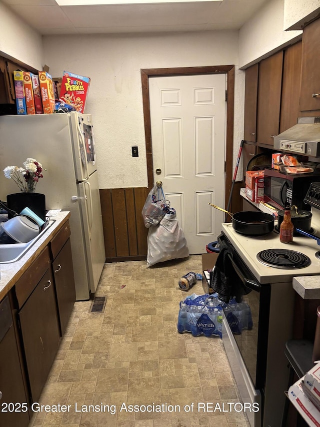 917 E Kalamazoo St, Lansing, MI 48912 - kitchen with electric range oven, black microwave, freestanding refrigerator, light countertops, and exhaust hood