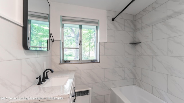 753 E Saginaw St, East Lansing, MI 48823 - bathroom featuring radiator heating unit, vanity, bathtub / shower combination, and tile walls