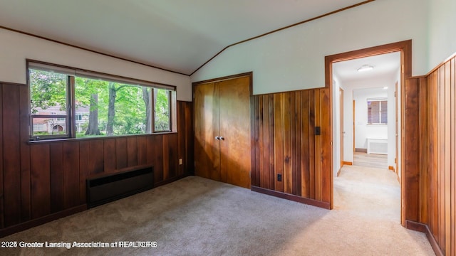 753 E Saginaw St, East Lansing, MI 48823 - unfurnished bedroom featuring a closet, vaulted ceiling, wooden walls, and carpet flooring