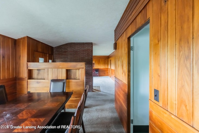 753 E Saginaw St, East Lansing, MI 48823 - dining space featuring wooden walls, vaulted ceiling, carpet flooring, and a textured ceiling